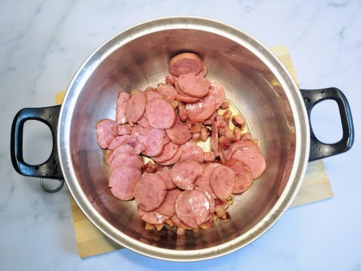Uma panela refogando o bacon e a calabresa.