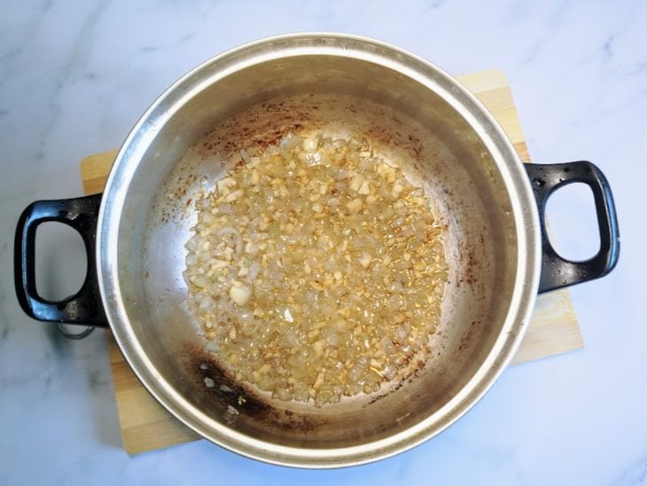 Uma panela refogando a cebola e o alho.
