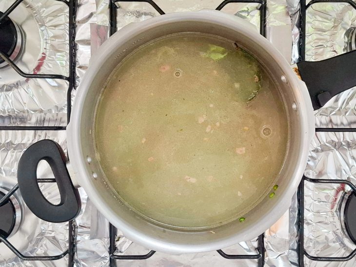 adição de água e louro para cozinhar ervilha na pressão.