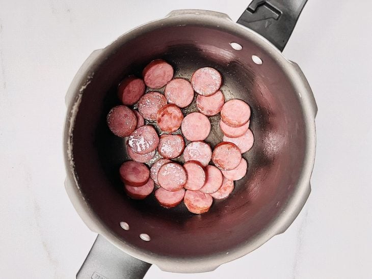Azeite e calabresa em uma panela de pressão.