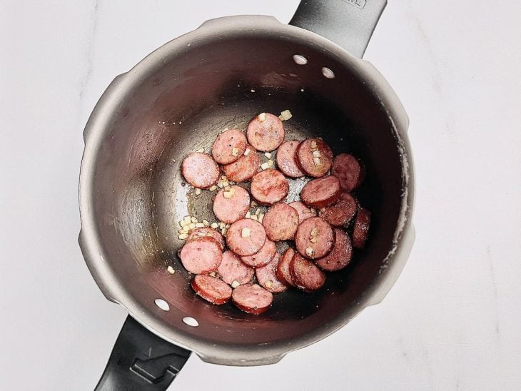 Alho, cebola e temperos adicionados na panela.