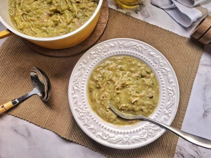 Uma panela e um prato contendo sopa de ervilha com frango.