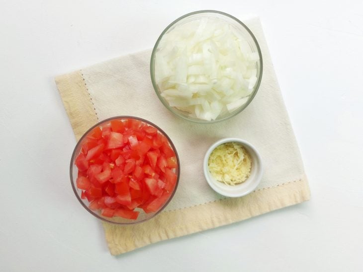 Recipientes com cebola, alho e tomate picados.