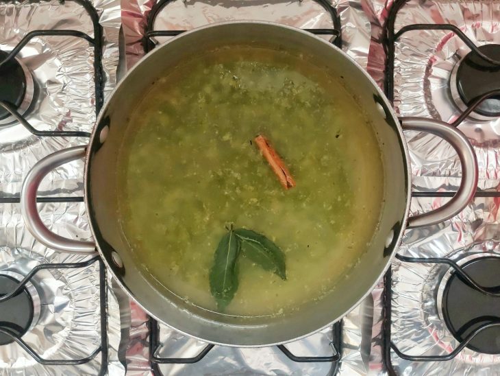 Uma panela com ervilhas, caldo de legumes, louro, sal e canela.