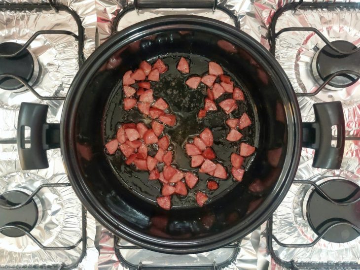 Uma panela com calabresa refogando.