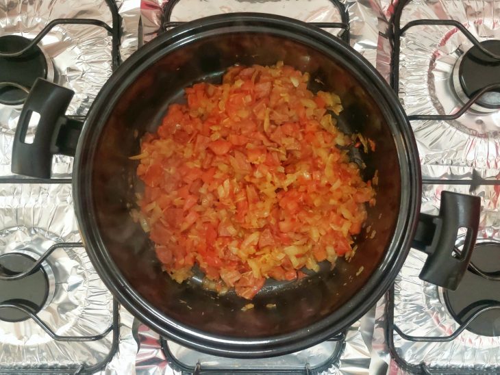 Uma panela com refogado de calabresa ao fogo.