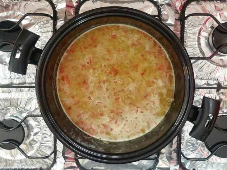 Uma panela com o refogado de calabresa misturado à sopa de ervilha ao fogo.