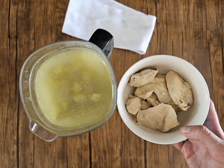 Frango retirado em uma vasilha e caldo colocado em um liquidificador.