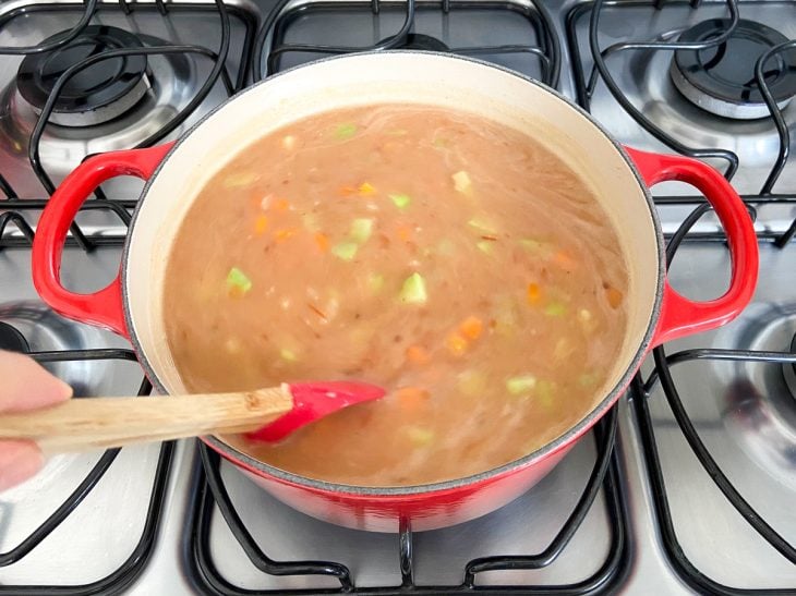 Uma panela contendo o caldo de feijão com ops legumes.