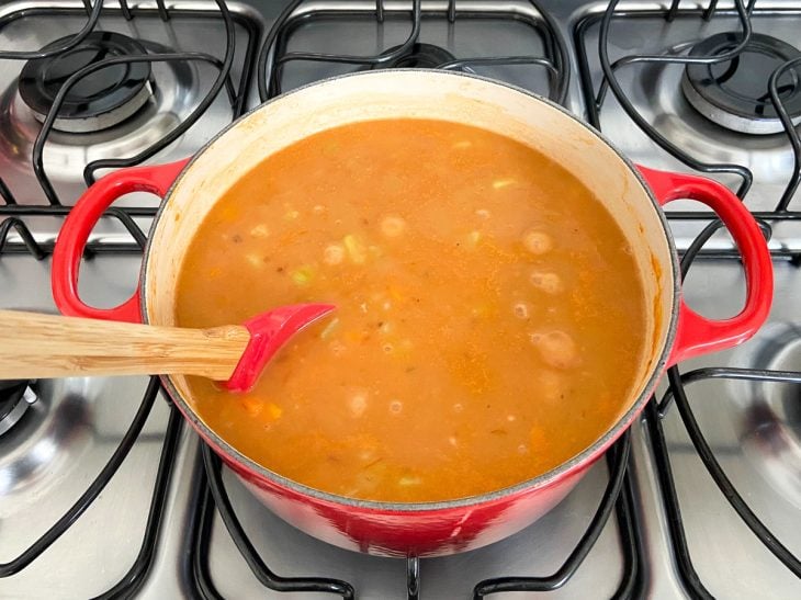 Uma panela contendo o caldo de feijão com ops legumes.