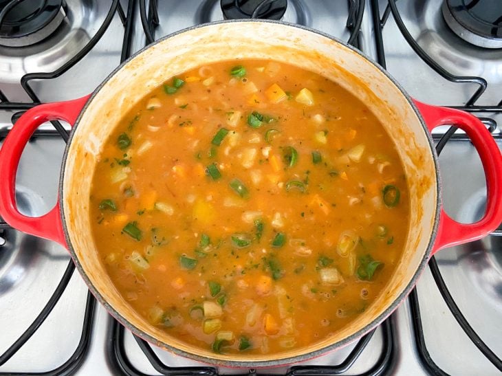 Uma panela contendo sopa de feijão com legumes.
