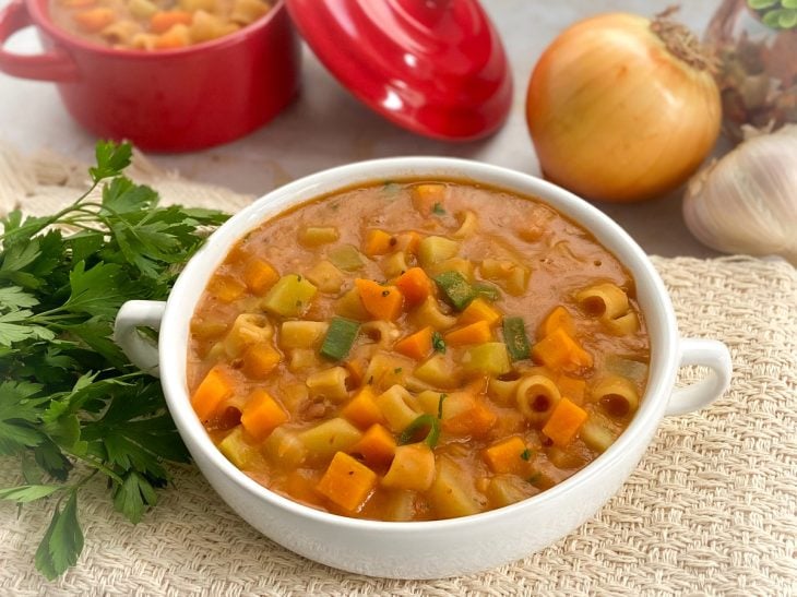 Um recipiente contendo sopa de feijão com legumes.