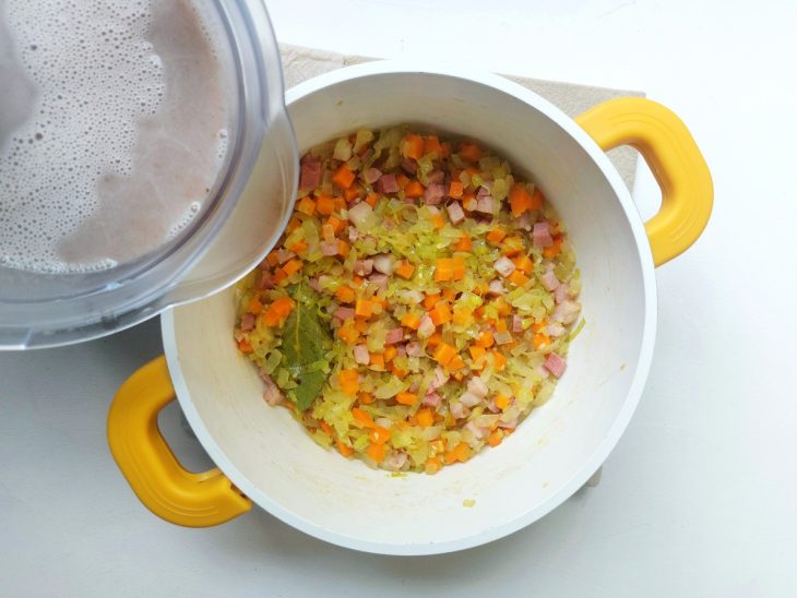 Feijão batido sendo acrescentado na panela com os legumes.