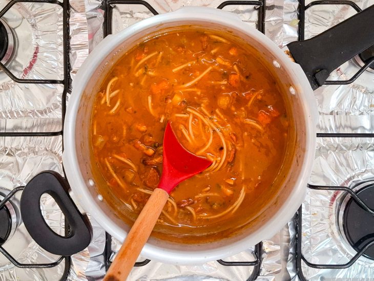 macarrão espaguete sendo cozido na sopa de feijão.