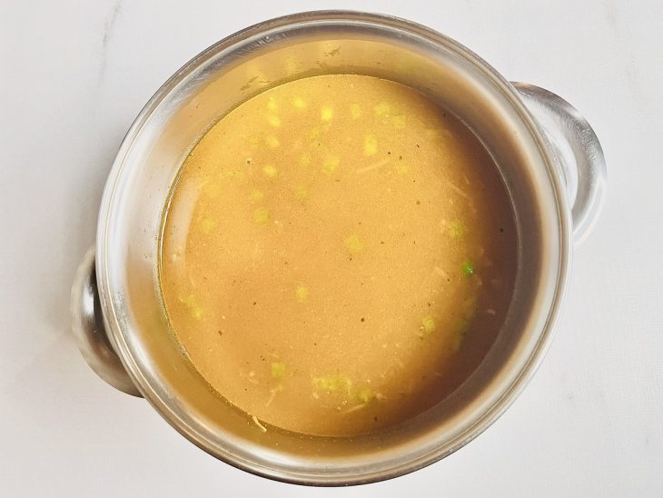 Pimentão verde, cenoura ralada e água na panela.