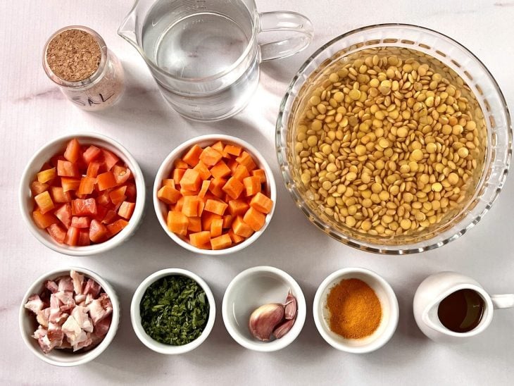 Ingredientes da sopa de lentilha com cenoura e especarias reunidos na bancada.