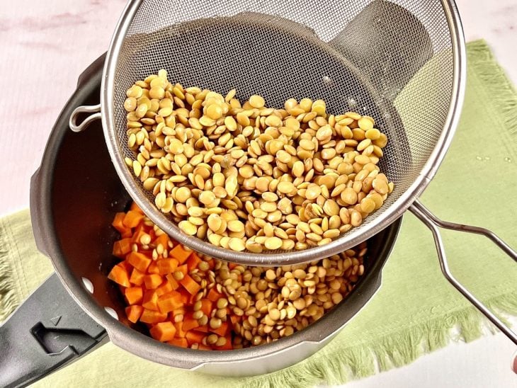 Lentilha sendo adicionada na panela de pressão com os demais ingredientes.