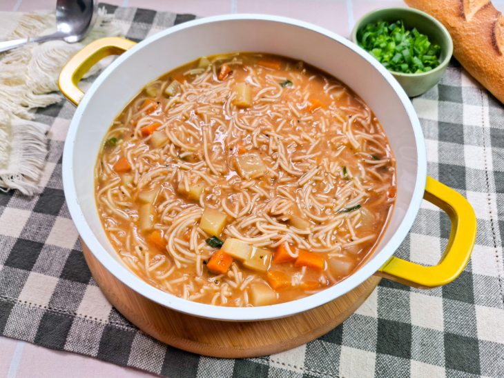 Sopa de macarrão finalizada com cebolinha e pronta para servir.