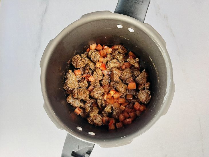 Alho, cebola e pimentões adicionados à panela.