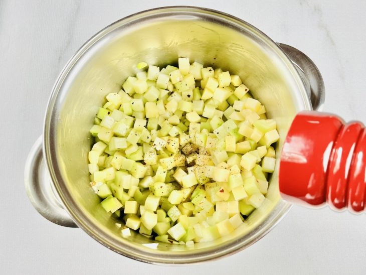 Batatas, chuchus e temperos adicionados na panela.