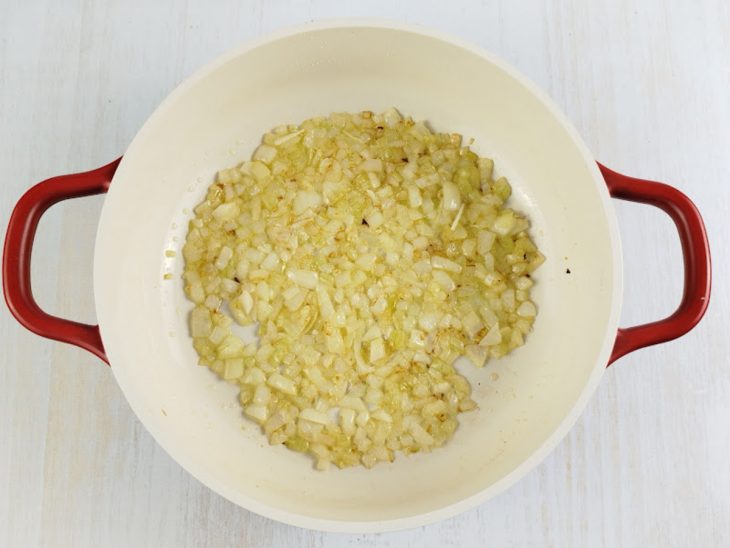 Cebola sendo refogada em panela com óleo.