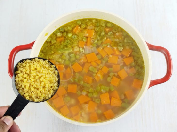 Macarrão sendo adicionado e misturado ao caldo quente.
