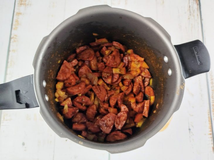 Tomate, colorau, sal e pimenta-do-reino adicionados a panela.