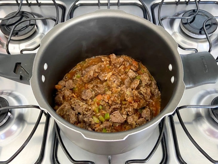 Panela com ingredientes sólidos e molho avermelhado.