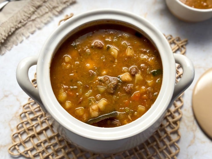 Panela de porcelana com sopa de músculo com legumes.