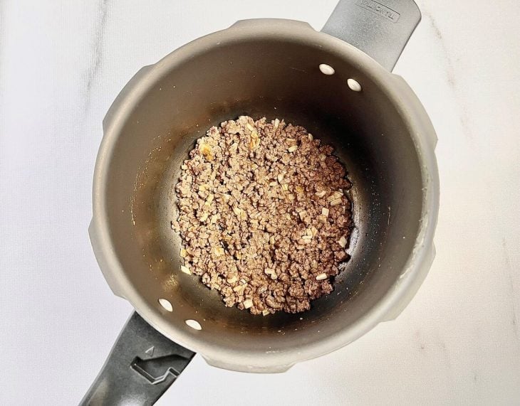 Carne moída e temperos adicionados na panela de pressão.
