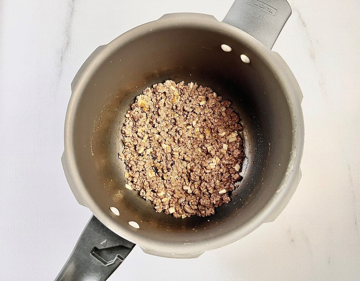 Carne moída e temperos adicionados na panela de pressão.