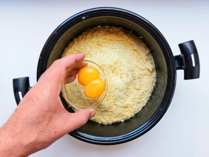 Queijo ralado e ovos sendo adicionados à panela.