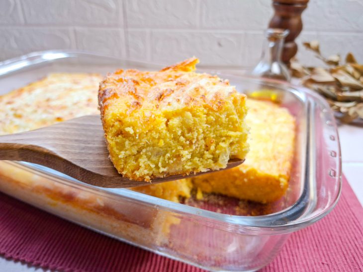 Fatia de sopa paraguaia sendo retirada na travessa.