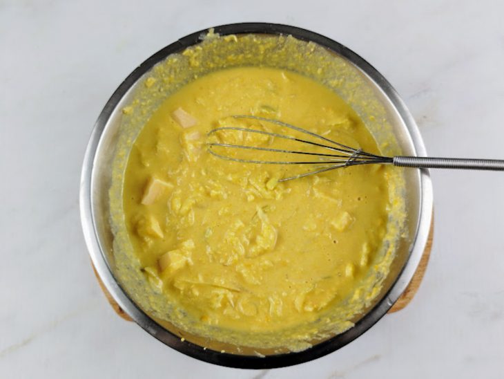 Ovos batidos e queijo adicionados a mistura do recipiente.