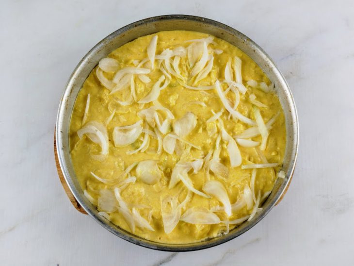 Cebolas picadas adicionadas sobre a mistura na forma.