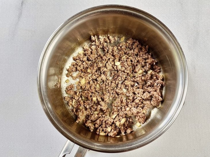 Uma panela com carne moída, cebola e alho a dourar.