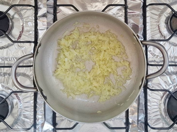 Alho e cebola refogados no azeite em uma panela.