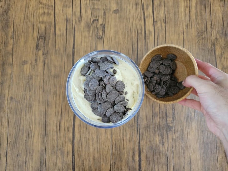 Chocolate em pedaços sendo adicionado à mistura de banana e leite em pó.