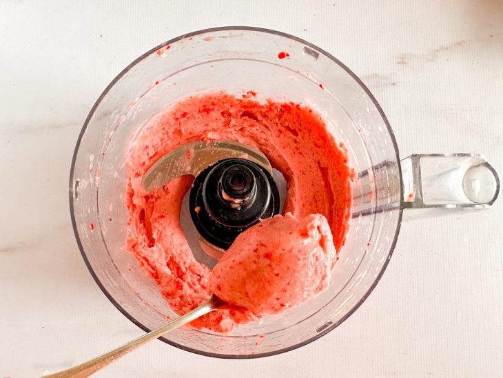 No processador, colher tirando uma porção do sorvete, mostrando a consistência.