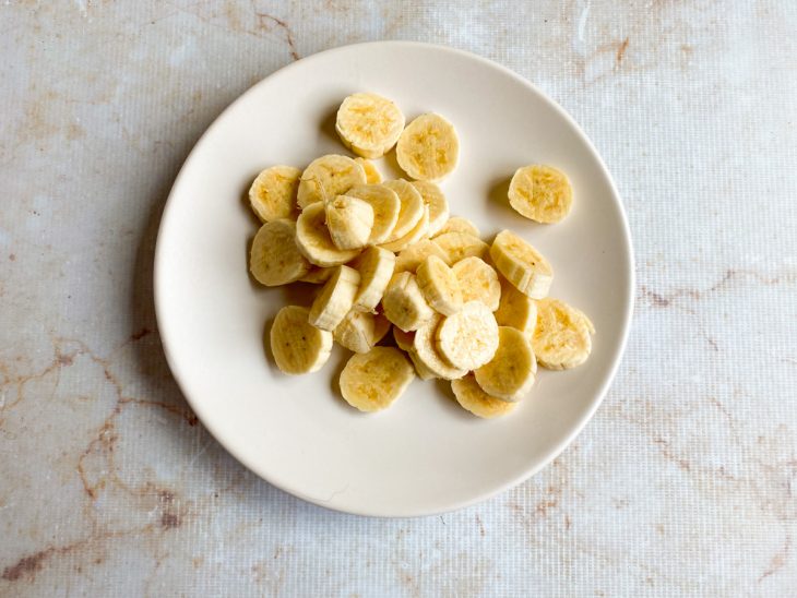 Bananas picadas em rodelas num prato branco.