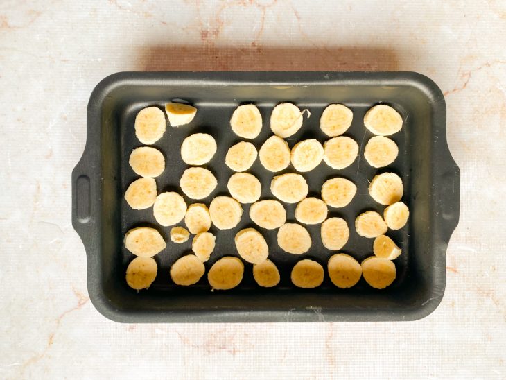 Rodelas de banana distribuídas numa assadeira.