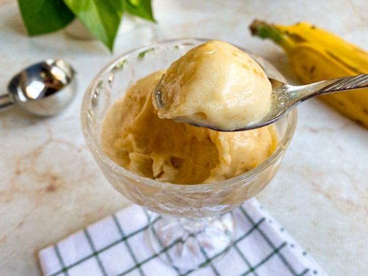 Sorvete de banana pronto para consumo com colher em destaque.