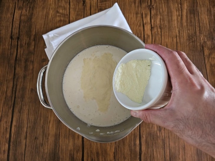 Um recipiente com creme de leite batido e leite em pó sendo misturado.