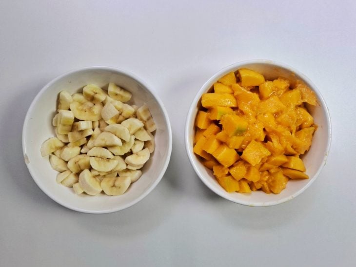 Manga e banana picadas e reservadas em recipientes distintos.