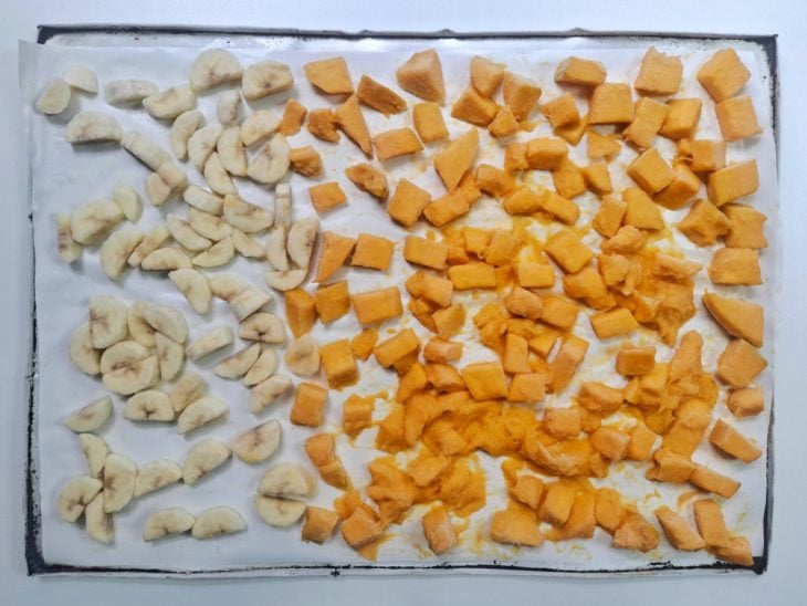 Frutas picadas distribuídas em uma assadeira.