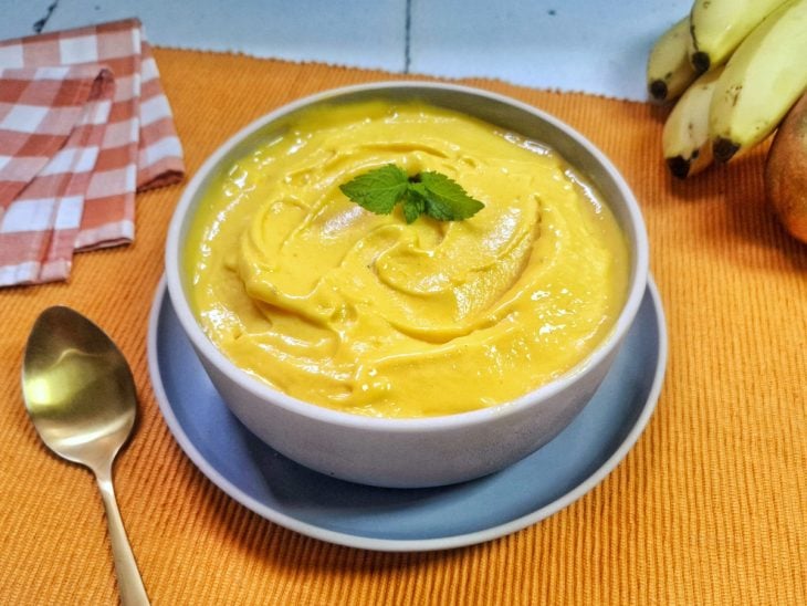 Sorvete de manga e banana finalizado com uma folha de hortelã, pronto para servir.