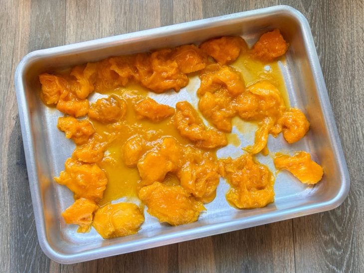 Pedaços de manga colocados em uma assadeira.