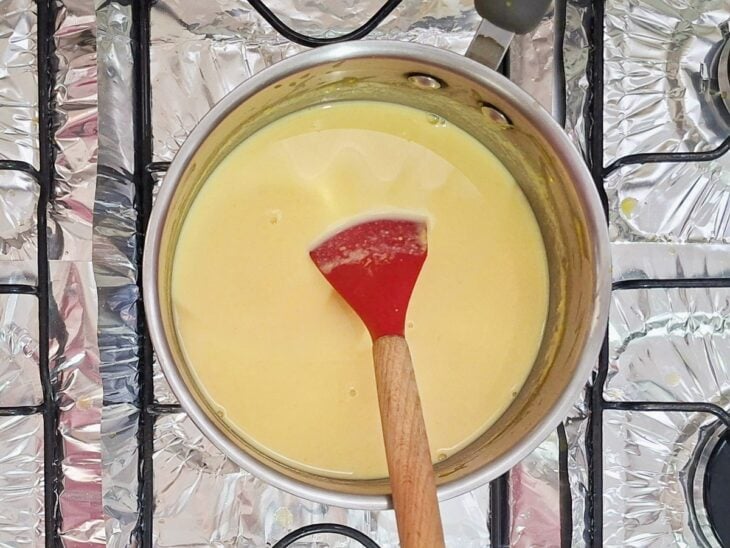 Creme sendo cozido e mexido até engrossar levemente e formar um mingau.