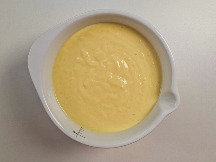 Creme de milho sendo transferido para um recipiente e coberto com plástico em contato.
