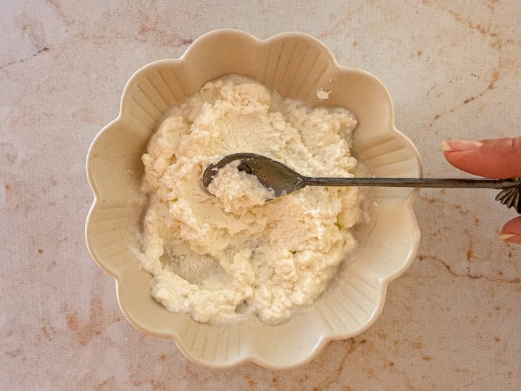 Suco de limão e sal sendo adicionados ao iogurte escorrido e misturados até formar um creme homogêneo.